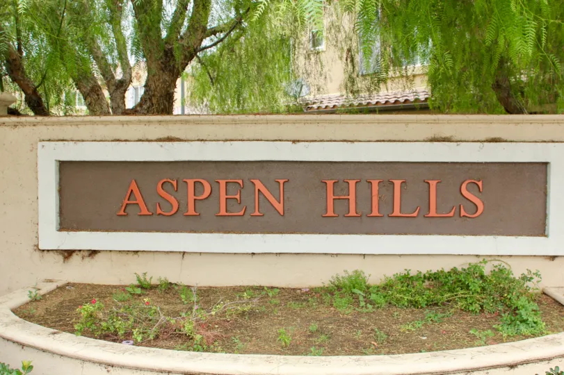 Cottonwoods surround the copper writing on the sign to the main entrance of Aspen Hills