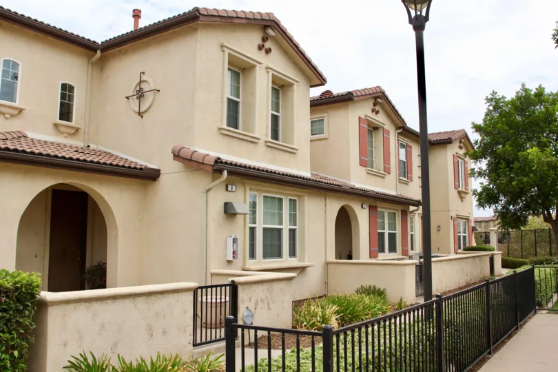 Front view of condos and padio areas with trees and fence