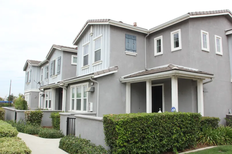 Bushes flank grey townhouses in the Iris Landing community
