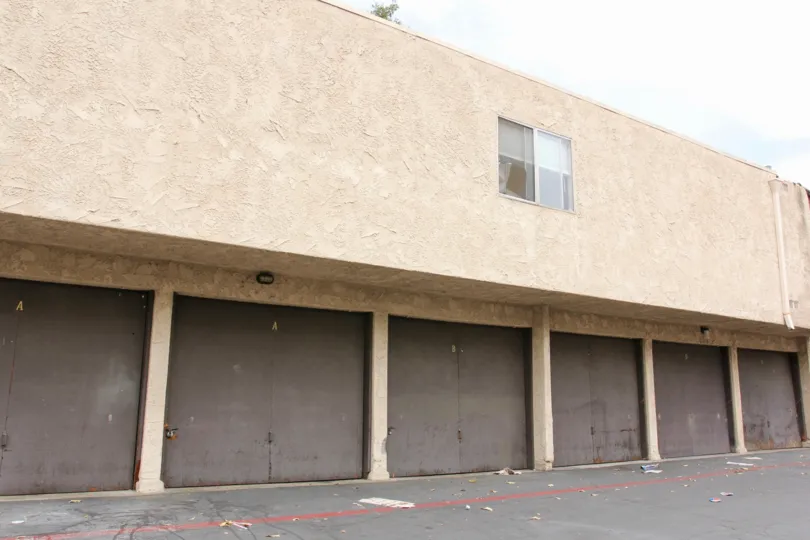 Rectangular apartment building with single window and brown garage doors