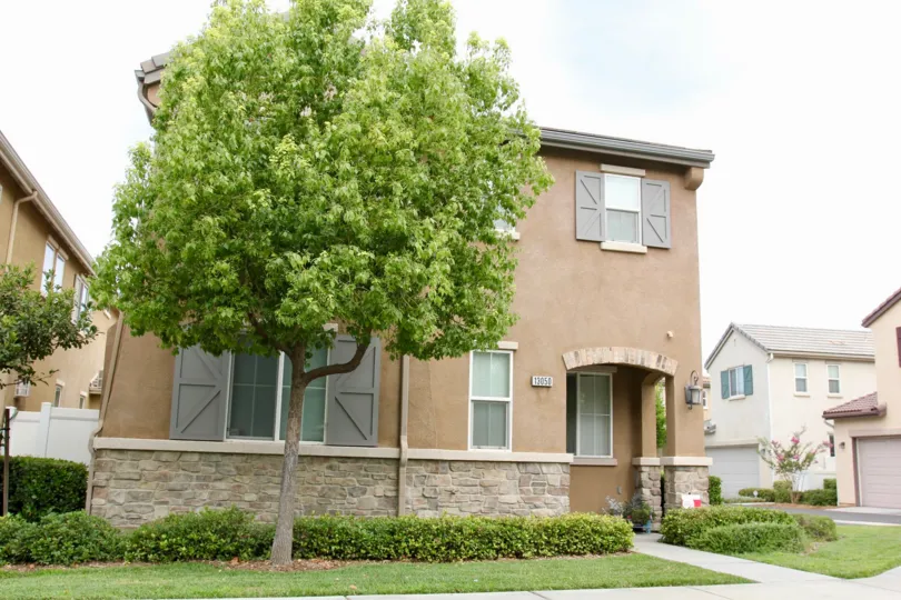 house is covered with grasses and in front there is atree and the door is covered by wakk