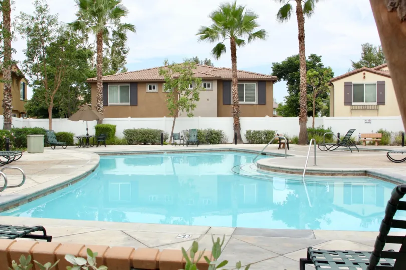 Fenced patio features a uniquely shaped pool with wide steps