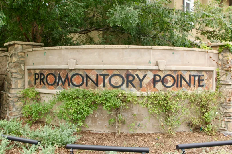 Promontory Pointe sign with leafy green vegetation in the daytime