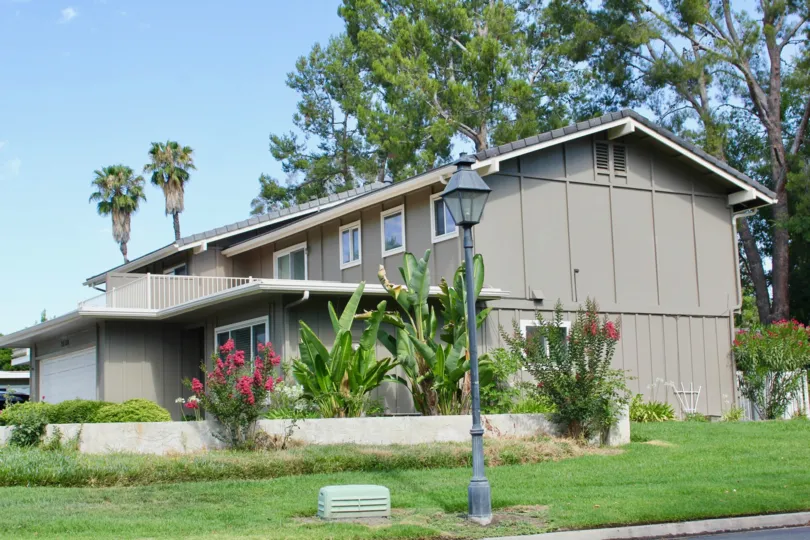 older house with green grass and banana trees with palm trees and large old trees