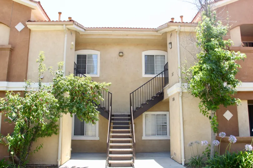house contains stair case at the front and surrounded by full of trees and grasses