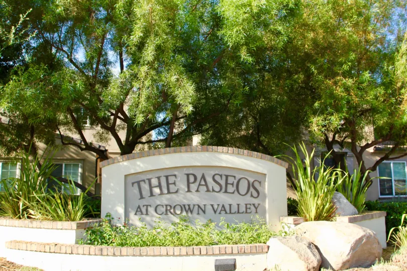 The paseos at crown valley is written on a sign in a garden