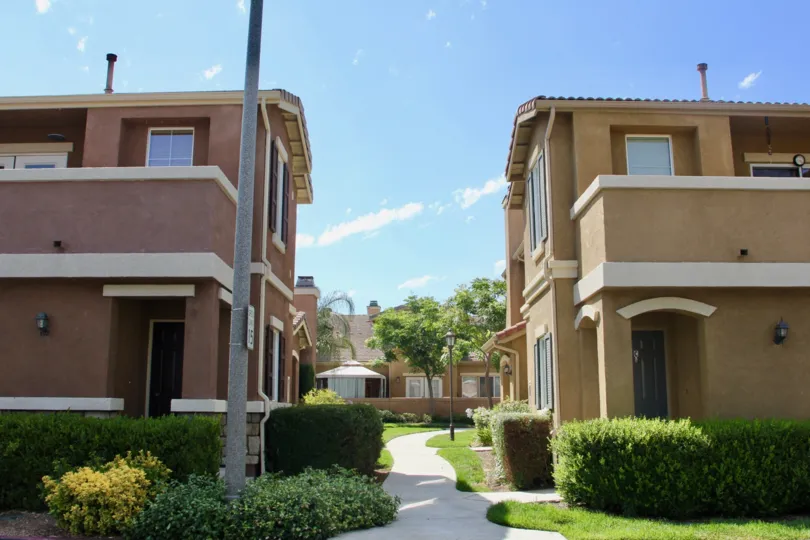 Twin villas with sidewalk and shrubbery in the Villas at Old School House community in Murrieta, CA.