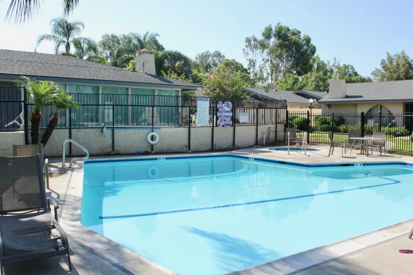 Sunny pool area with hot tub and community center with beach chairs
