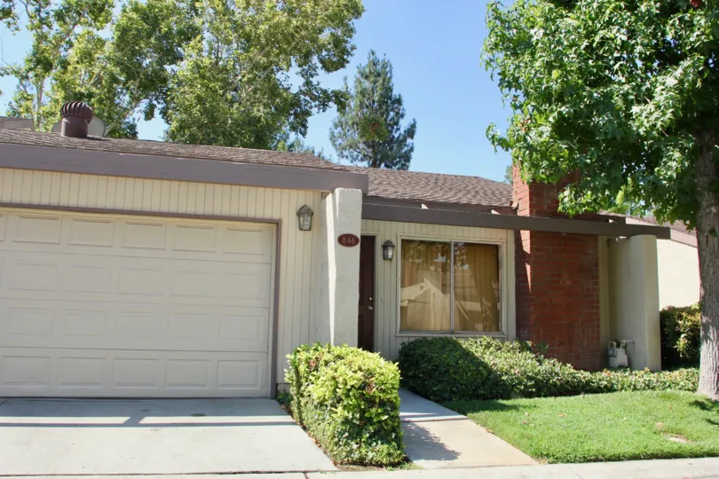 A brick chimney sits on the front of a beige house in the Crest View Estates.