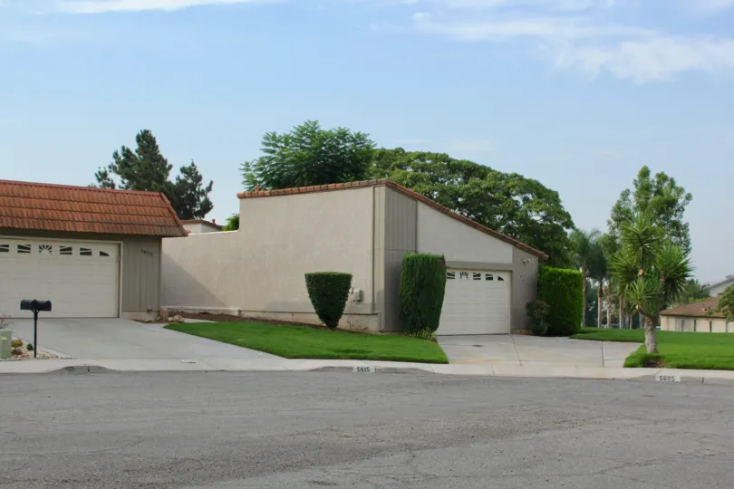 Ending coldesac features large garages and shrubs and trees between houses