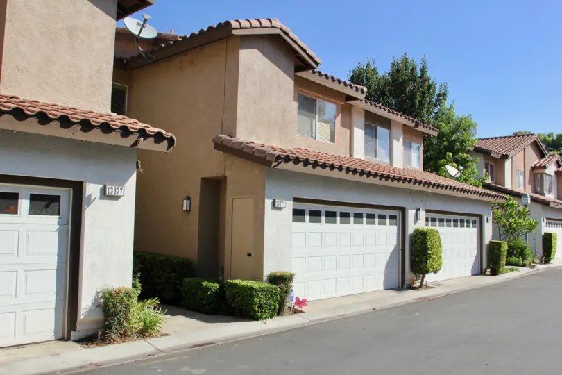View of garages from street on a clear day of Townhouses at Four Seasons Villas.
