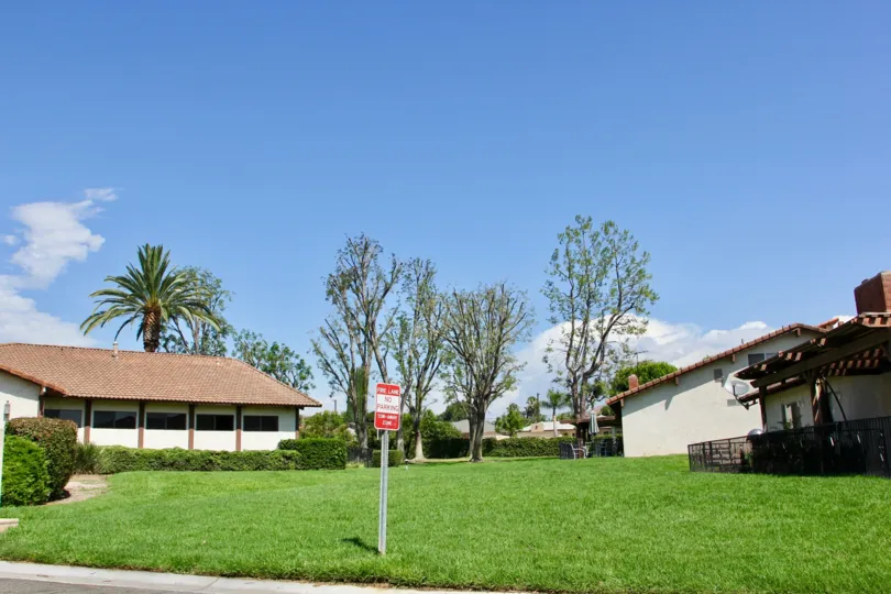 sunny grassy area of the Orangewood Villas with a no parking sign