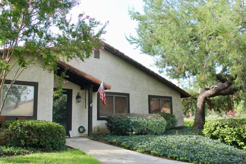 California garden homes and american flag adorn this home with slantey roof and large downstairs windows