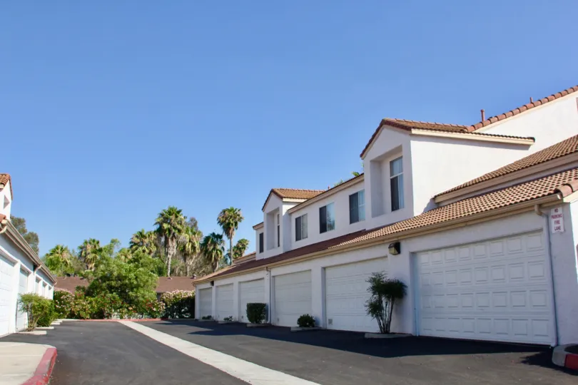 Large garages in Rancho Del Mar on a cloudless day with trees in the background