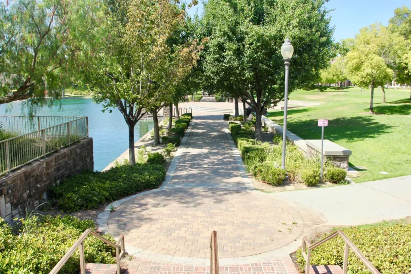 Trees line either side of a brick path near a pond at Savannah at Harveston.