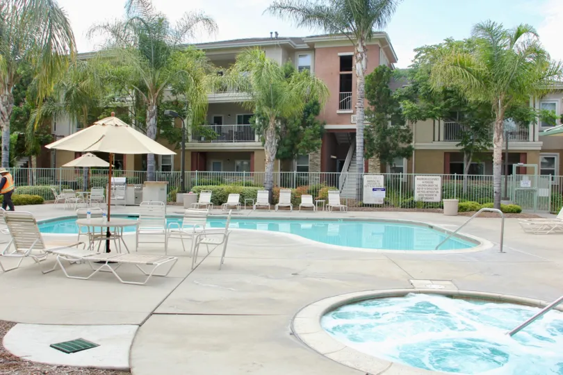there is large swimming pool in front of house and there is a chair for sitting and getting relaxed and house contains staircase and is surrounded by trees and grasses