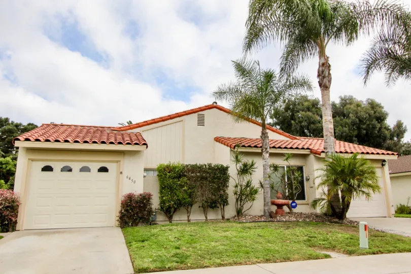 Cloudy day outside a ranch style house in Alta Mira Carlsbad California with green bushes and palm trees