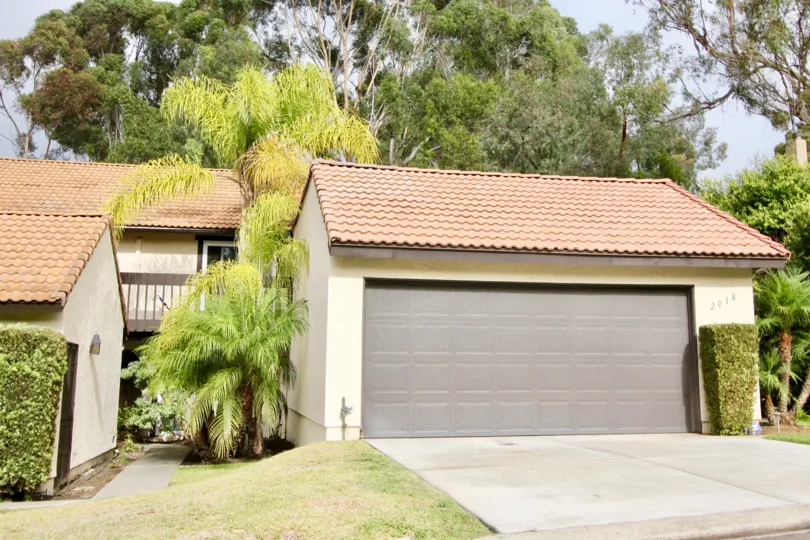 A garage surrounded by palm trees with more trees behind it on a sunny California day
