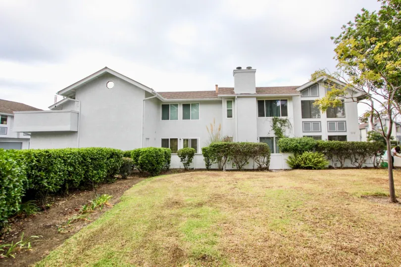 THE BUILDING IN THE CARLSBAD CREST WITH THE GRASSLAND, PLANTS, TREES, WINDOWS