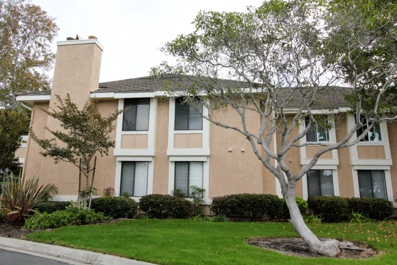 THE BUILDING IN THE CARLSBAD CREST WITH THE TREES, LAWN, THAR ROAD