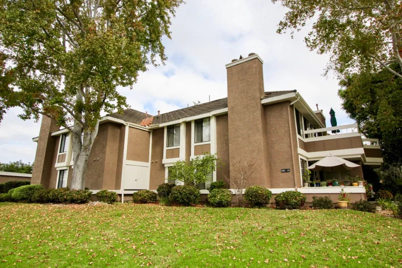 THE BIG HOUSE IN THE CARLSBAD CREST WITH THE GRASSLAND, PLANTS, UMBRELLA, TREES