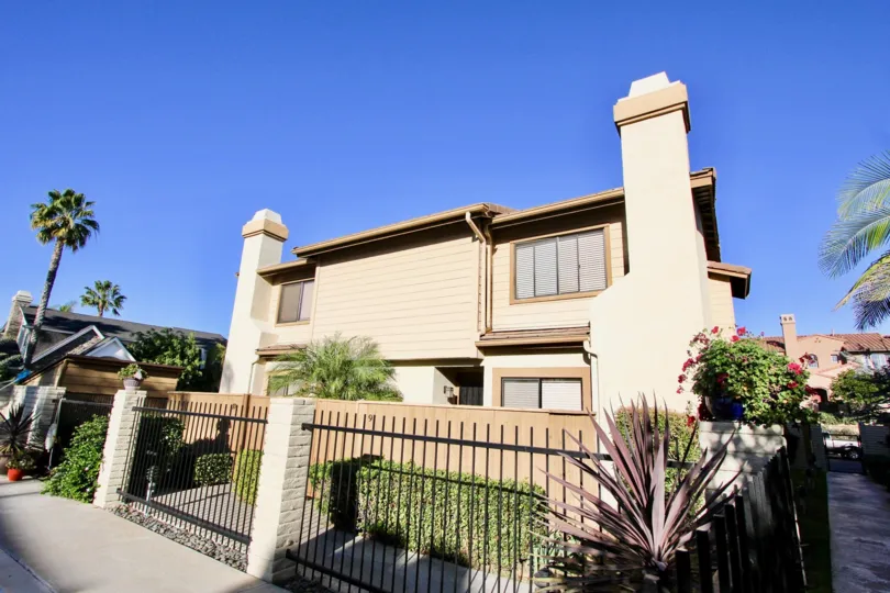 clear blue sky day outside of a fenced in two story home in Carlsbad California