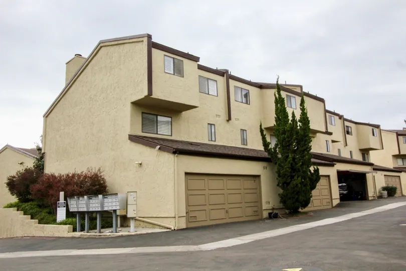 two story duplex apartment with 2 car garage windows near mail box, adobe style