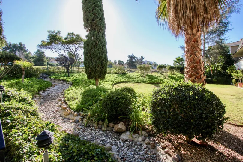 Expansive community green space with river rock lined paths and mature trees and wide views at Costa Verde