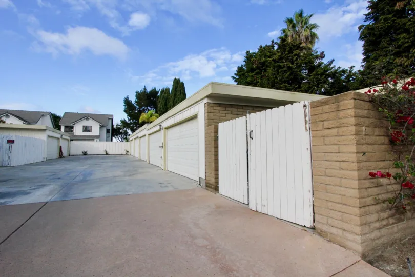 THE BUILDINGS IN THE EL OASIS WITH THE EMPTY SPACE, WOODEN DOOR, FLOWER PLANTS, TREES