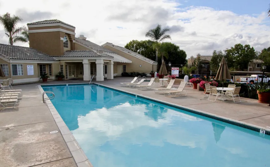 Lounge chairs sit by the long, clear blue pool of the La Costa Alta community in Carlsbad, California.