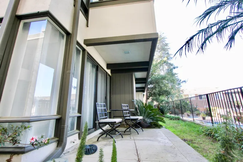 Patio view outside a unit overlooking the community swimming pool and lawn at La Costa Fairways