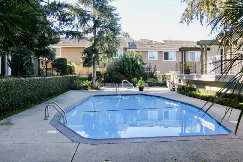 THE APARTMENT IN THE LA COSTA FAIRWAYS WITH THE SWIMMING POOL, STEEL WALL, FLOWER POT, TREES