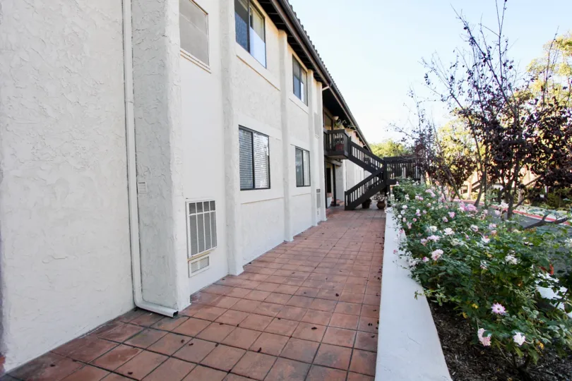 A SIGHT OF CORRIDOR OF A WHITE COLOURED BUILDING WITH GREEN AREA