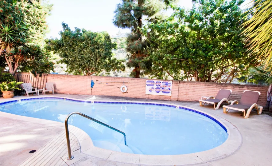 A pool's safety rules and some lounge chairs sit in front of a small pool in the La Costa South community of Carlsbad, California.