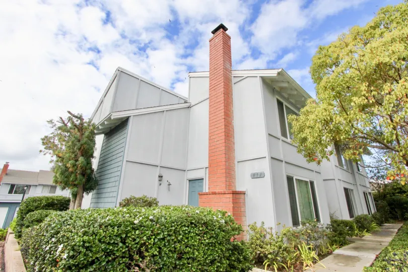 A SIGHT OF A BACKYARD OF A BUILDING WITH RED COLOURED CHIMMNEY & WITH GREEN PARK