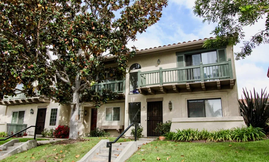 Sunny sky with an apartment building and a tree in the Las Playas Community in Carlsbad, CA.