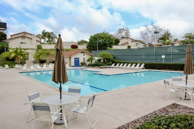 There are many chairs placed near the Swimming pool and umbrella is closed on dining table belong to Las Playas