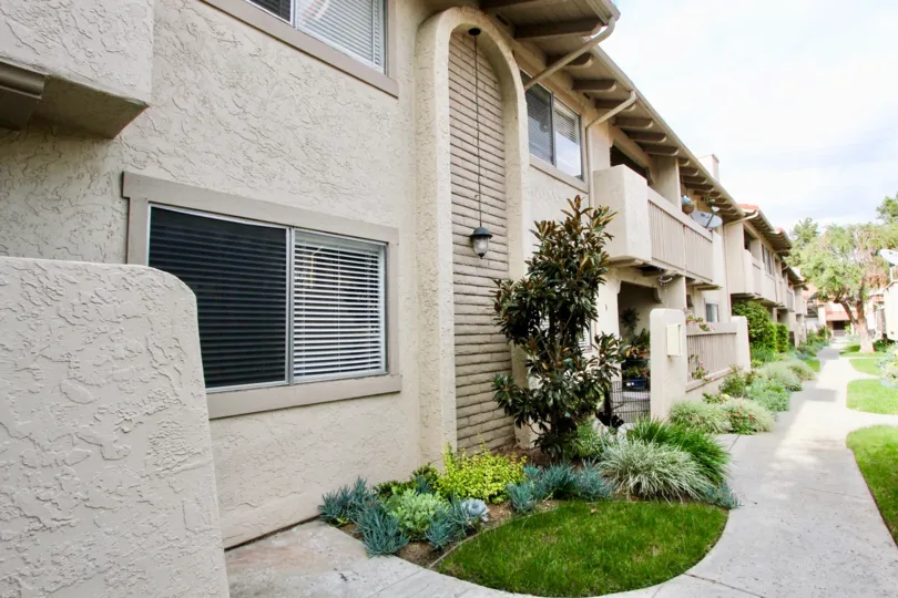 A BACKYARD OF A CREAM COLOURED APARTMENT WITH GREEN AREA