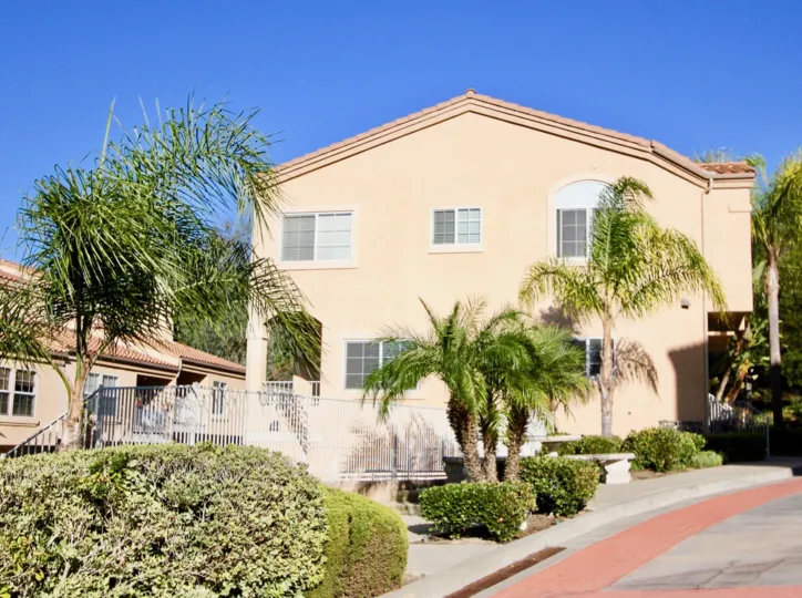Classical California residence in Carslbad, with palm trees and gated fence.