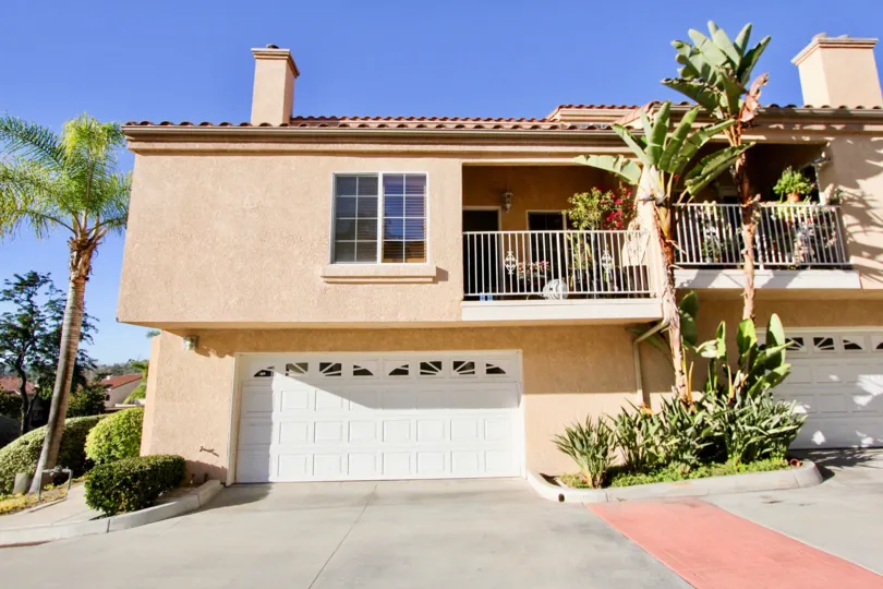 A spacious two story brown condominium building with a white garage door in Meadowview Townhomes in Carlsbad CA