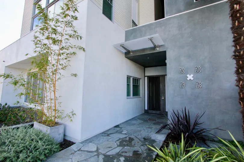 A gray building with a stone sidewalk leading up to it at Railyard Loft in Carlsbad CA
