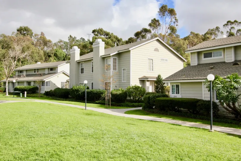 There are three houses and has meadow, light lamps, trees and plants near and opposite to it in The Crest