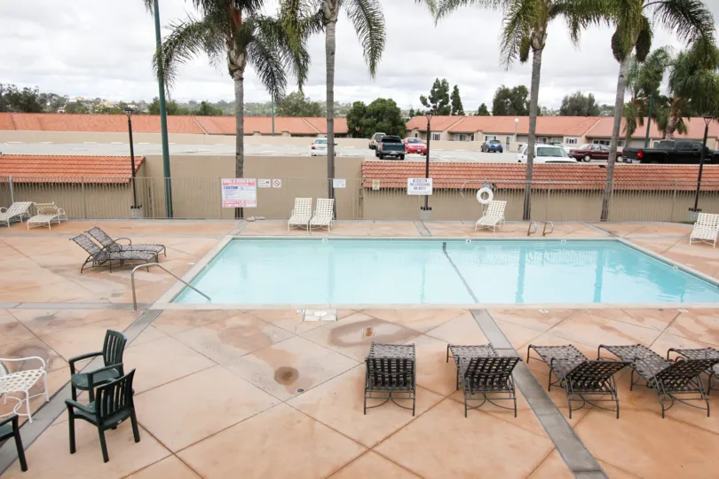 A cloudy day in the Grove with a blue color swimming pool with chairs.