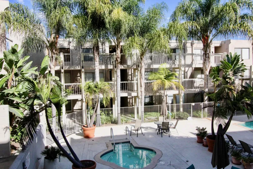A small swimming pool near a big apartment in the Tres Verde with some plants and trees.
