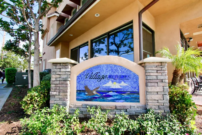 A beautiful day in the Village by the Sea with a signage in front of a building.