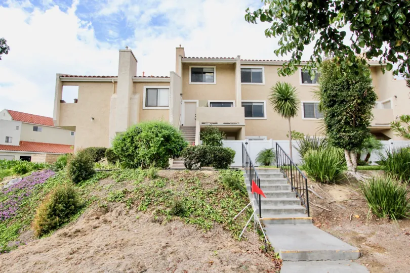 THE BUILDING IN THE WEST BLUFF HILLS WITH THE STEPS, FLAG, PLANTS, TREES