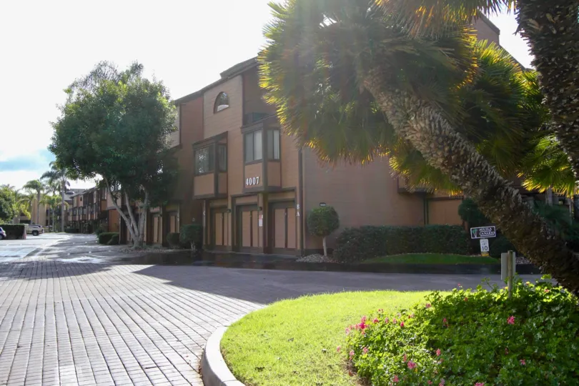 A bright day in the Windsong Palms with a beautiful tree and building.