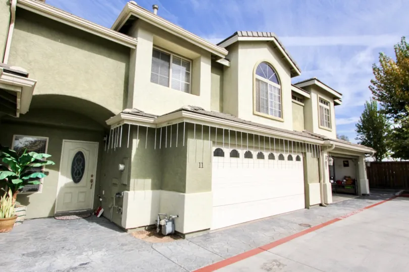 A white door with an ornate window sits on an olive green townhome at Ada Terrace