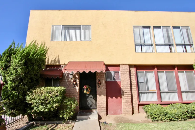 Amber building with front gate with trees, Chula Vista, CA