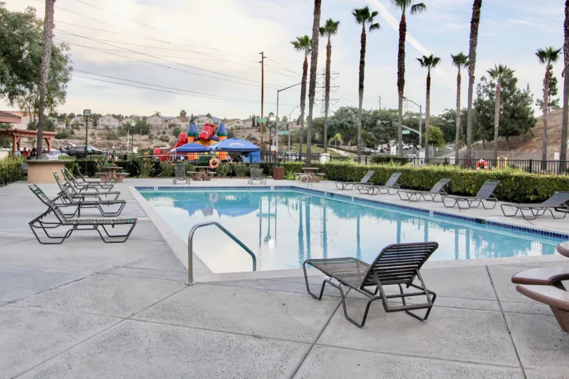 Pool at Antigua in Chula Vista, Ca with patio chairs and view of palm trees.